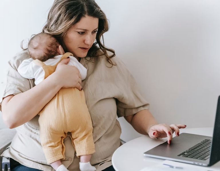 person holding baby while using laptop